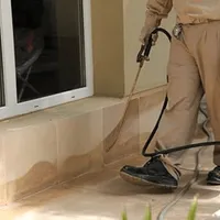 General pest control technician spraying exterior perimeter around a home in West Palm Beach, FL